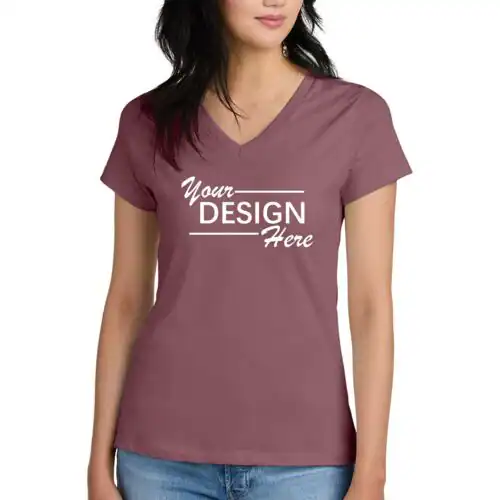 A woman wearing a mauve V-neck T-shirt with "Your Design Here" printed in white on the front. She stands with one hand by her side, showcasing custom T-Shirts Manhattan & Long Island, NY, paired perfectly with blue jeans.